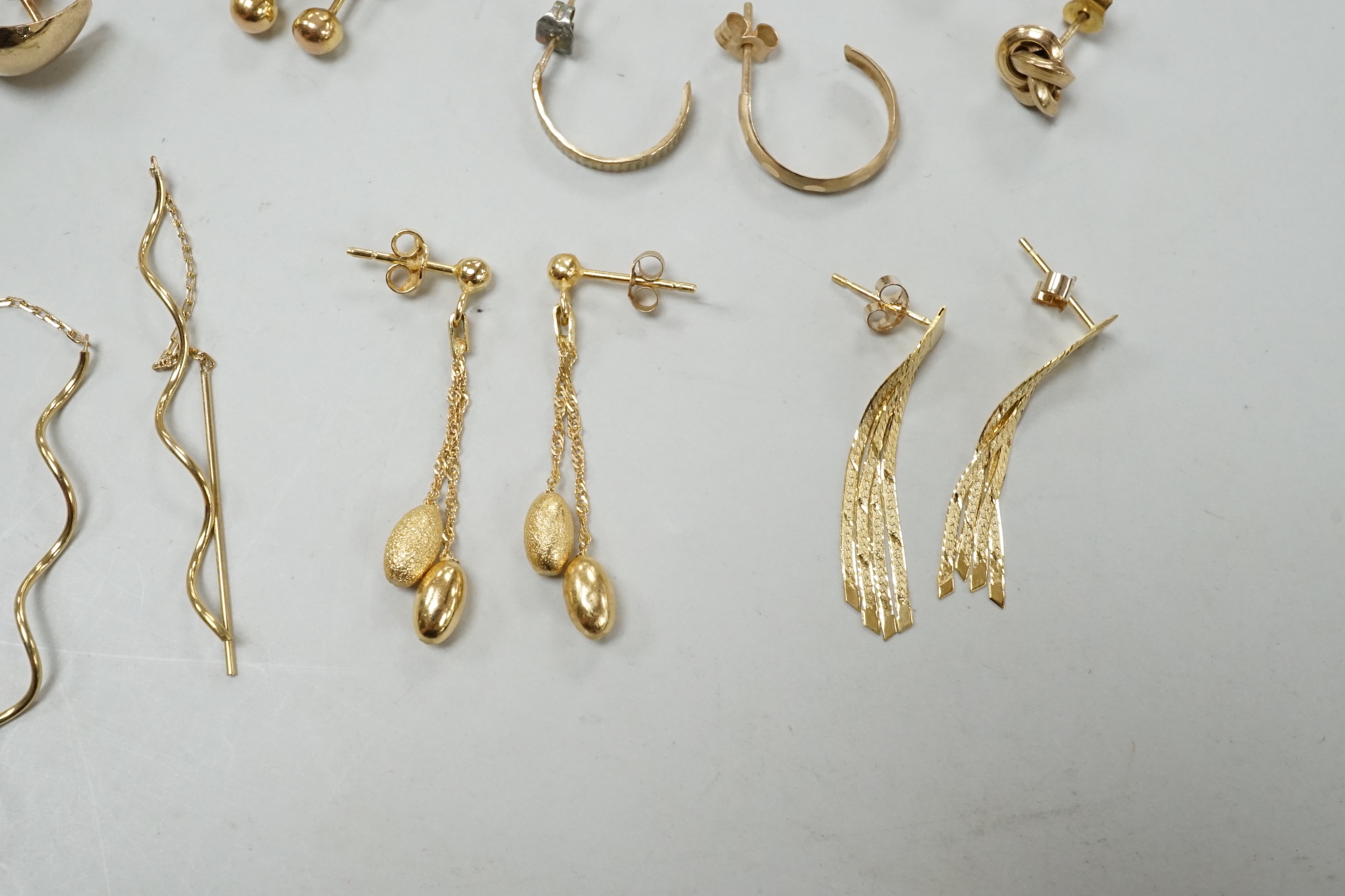 Seven assorted modern pairs of 9ct earrings including tassel drop and pear shaped, 12.7 grams and ten other yellow metal pairs, three odd ear studs and a small heart pendant?